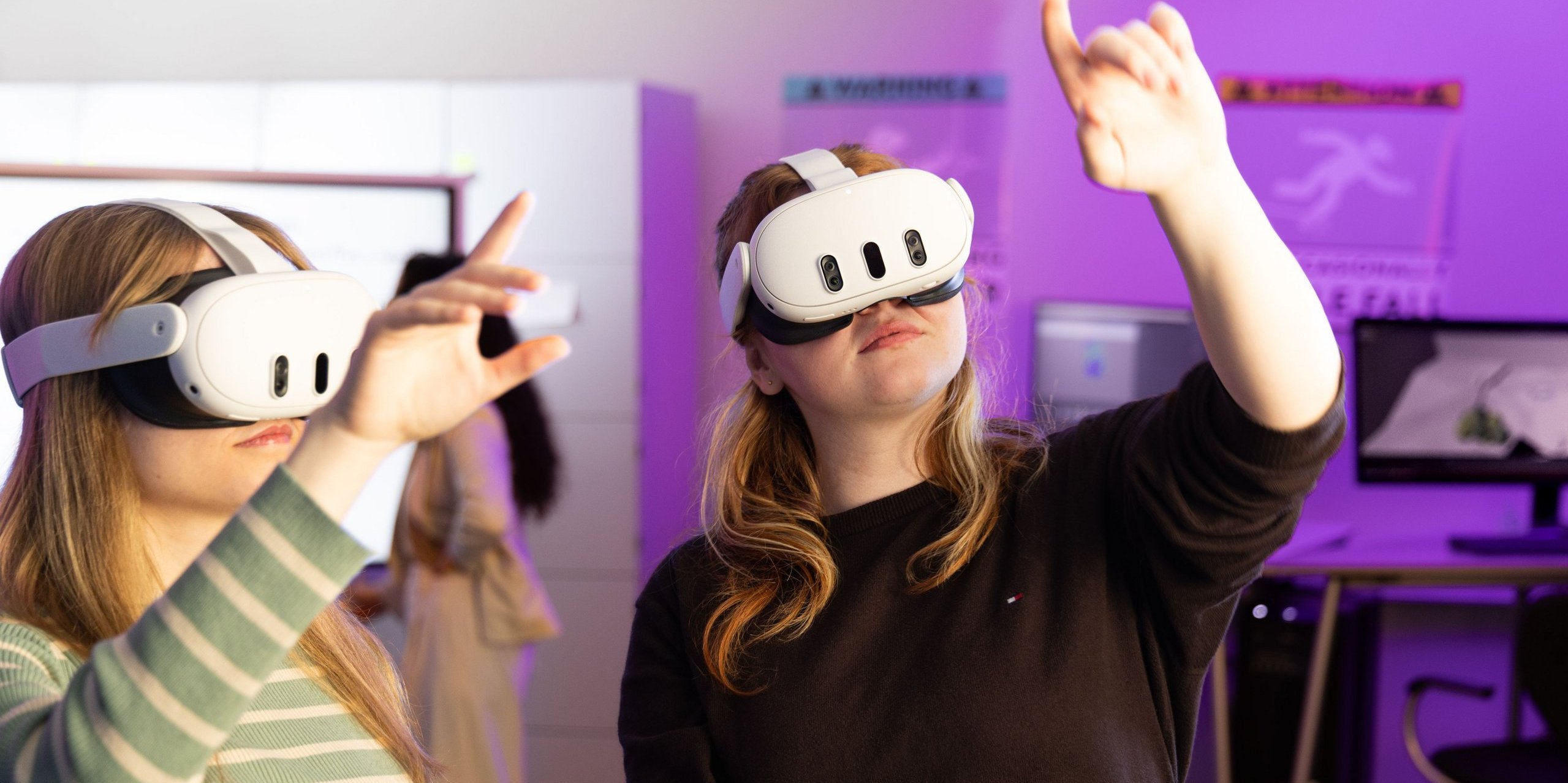 zwei Personen mit VR-Brille recken jeweils eine Hand in die Luft