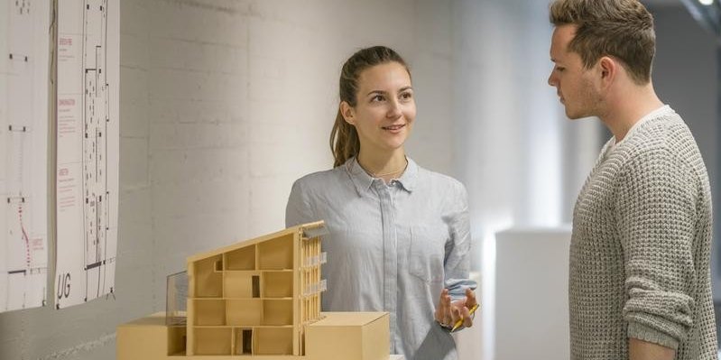 Zwei Studierende diskutieren ein Architekturmodelll