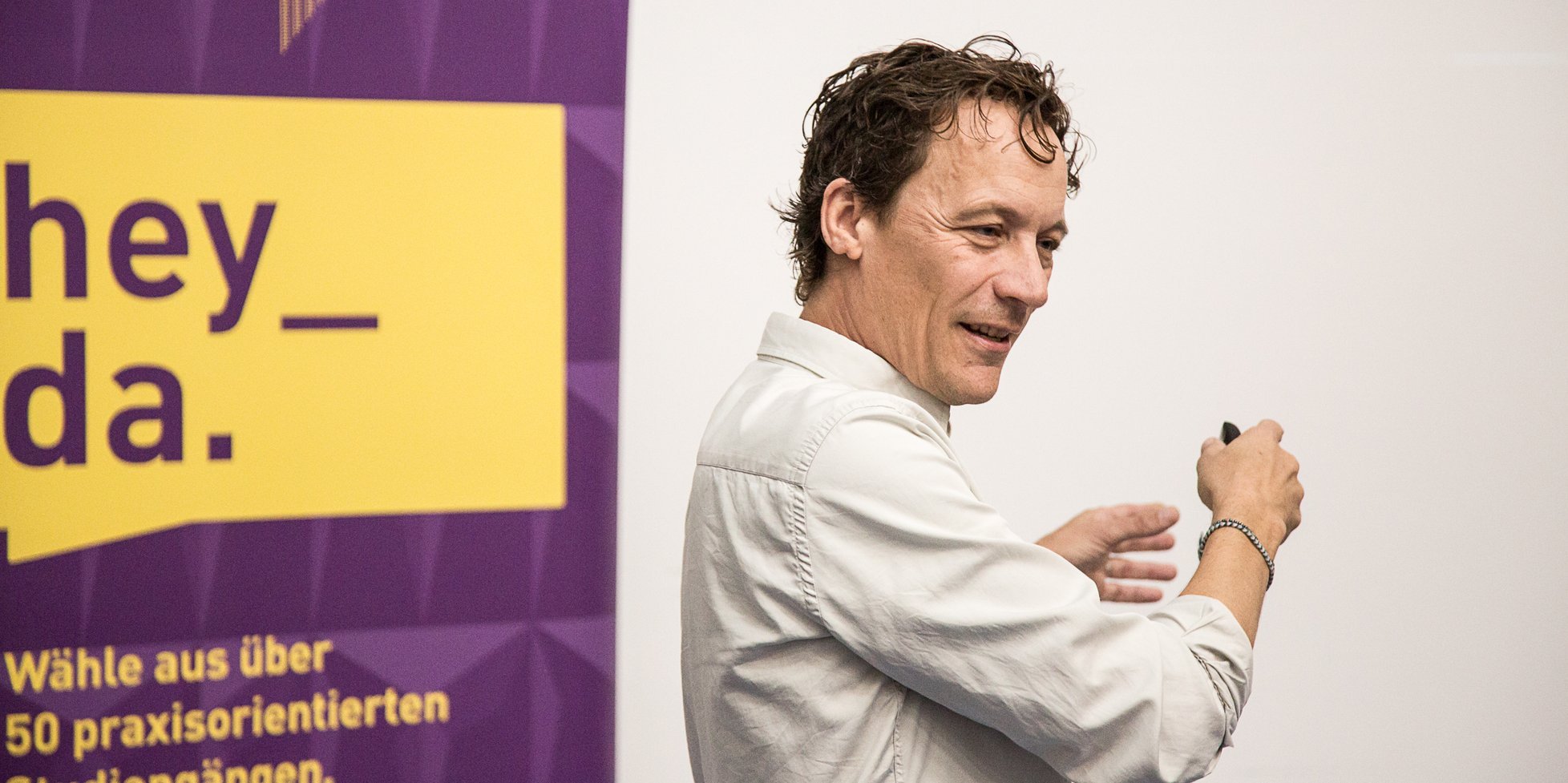 Mathias Ihrig stehend vor einem Plakat der Studienberatung