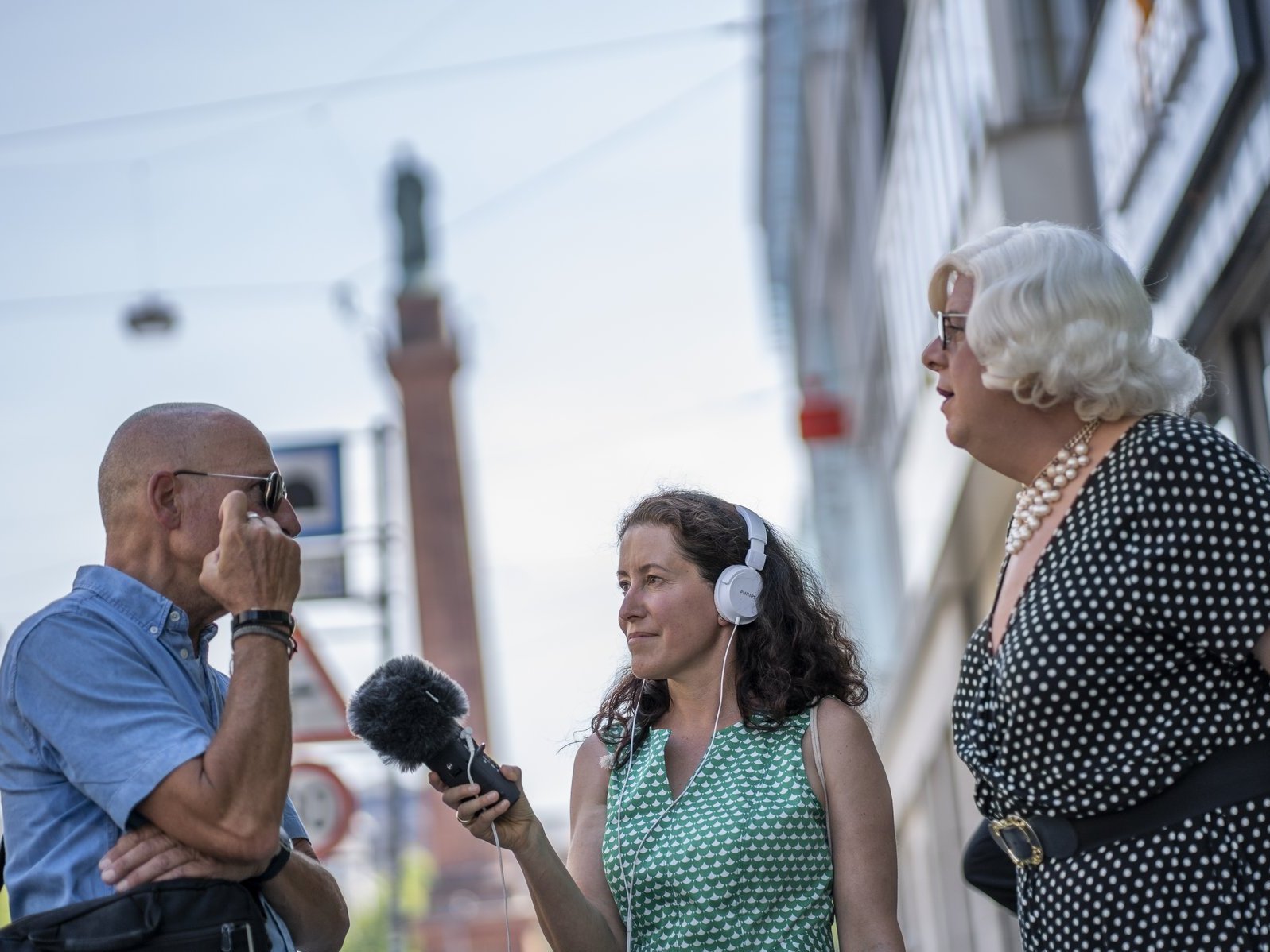 Das Foto zeigt Moderatorin Christina Janssen mit Professor Hartmut Raiser und Entertainerin Aurora De Meehl, im Hintergrund sieht man den Luisenplatz. 