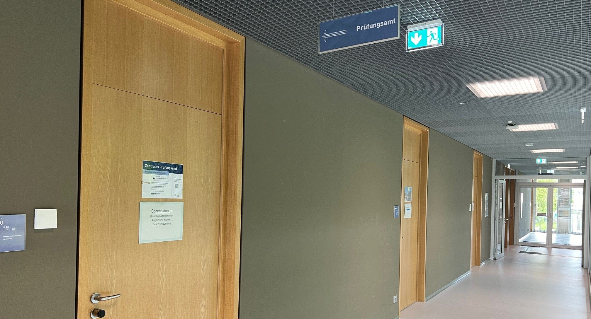 Fluransicht im Gebäude C23 1. Stock mit dem Schild Prüfungsamt mit Pfeil auf den Raum 1.20